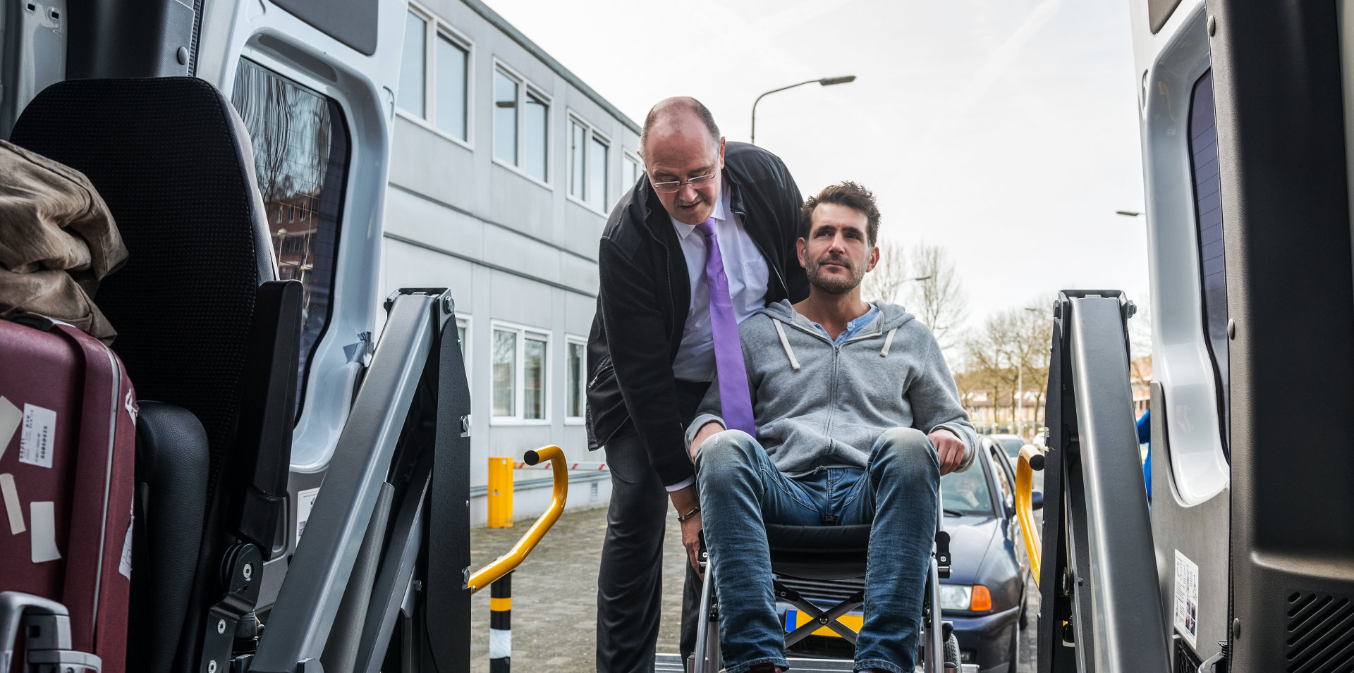 man helping a disabled man on wheelchair in boarding a van