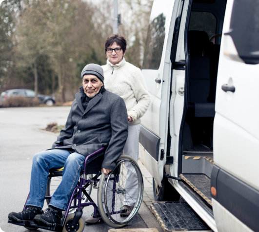 senior man sitting on a wheelchair together with her carer